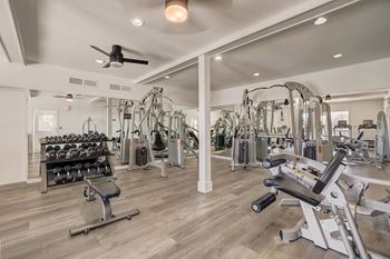 a gym with weights and cardio machines and a ceiling fan